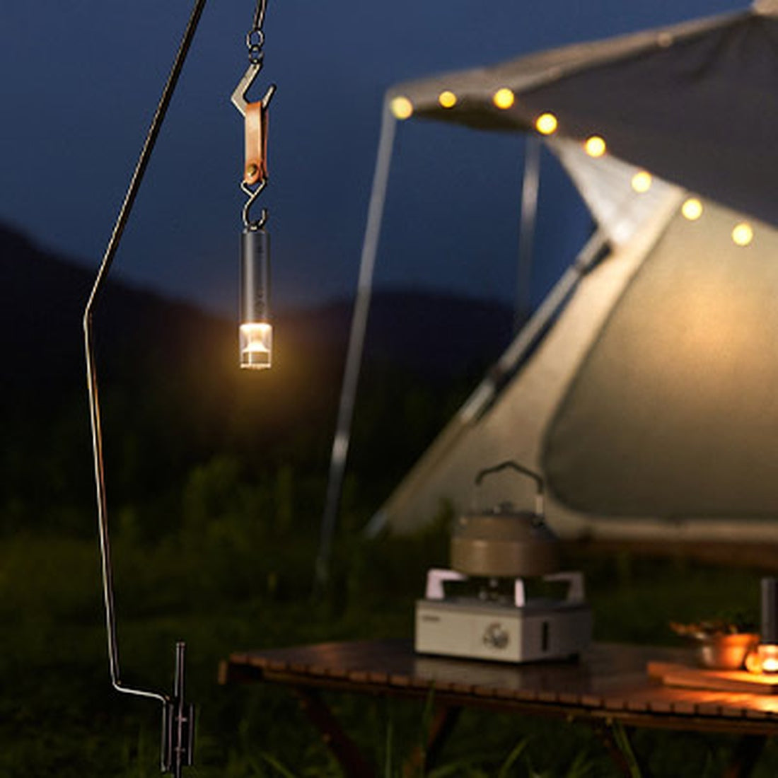 Mijia portable flashlight suspended by its hook at a campsite; camping props not included