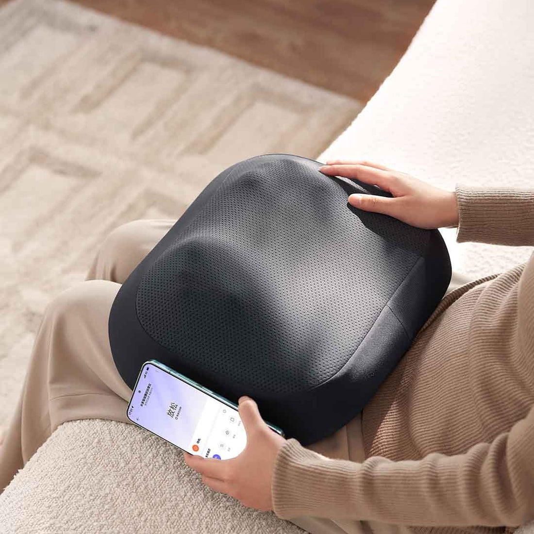 Mijia Smart Waist Massager cushion on a sofa, manufacturer illustration with app controls