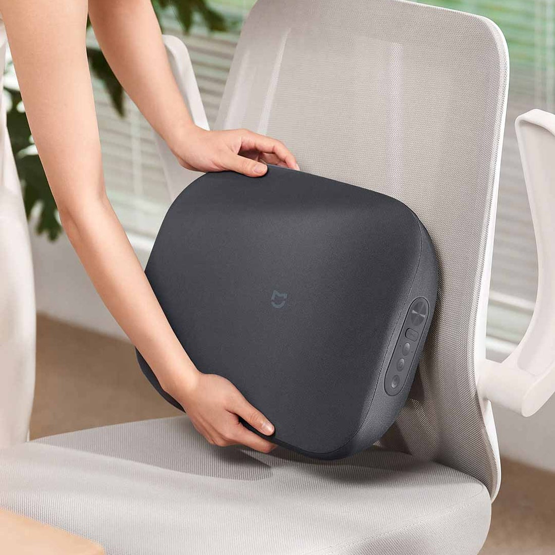 Mijia Smart Waist Massager being positioned on a chair as lumbar support