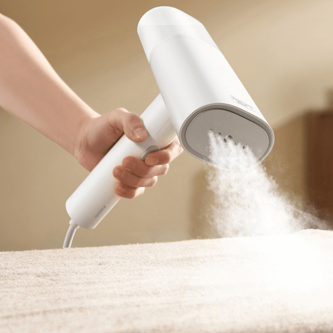 Xiaomi handheld garment steamer releasing steam above fabric; shared manufacturer illustration
